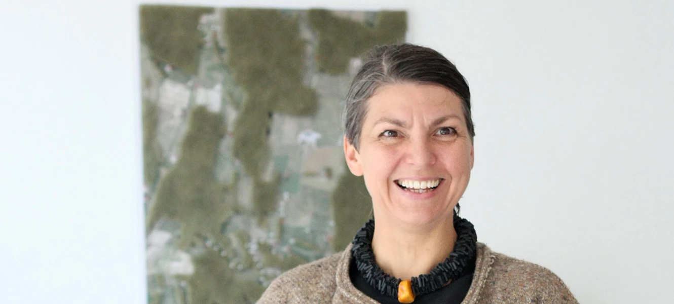 Christina Korsbek Olsen står foran et farverigt abstrakt maleri.