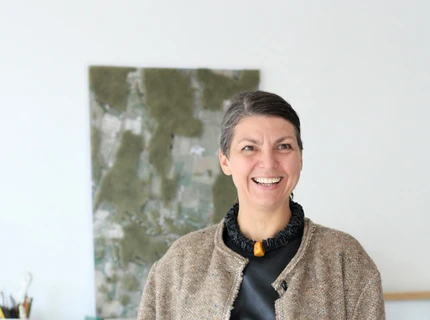 Christina Korsbek Olsen står foran et farverigt abstrakt maleri.